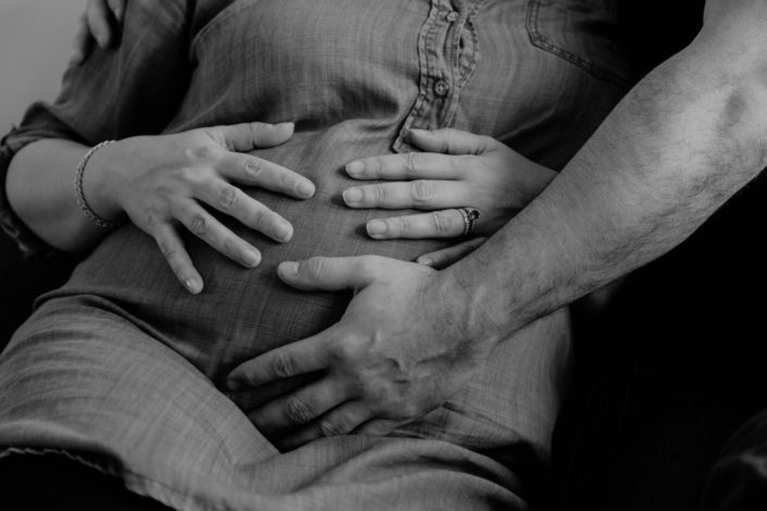 Les mains de maman et papa posées sur le ventre. Une photo parfaite pour une séance photos grossesse parfaite.